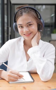 Image of a young woman studying online using a tablet. Looking at the camera..