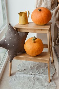 Autumn interior in a photo studio, with pumpkins, a vase and a wooden stool.