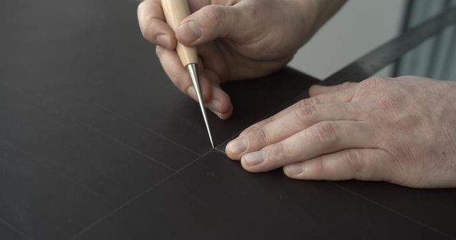 Working process of crafting a bew handmade leather wallet in the leather workshop. Concept of small business to create leather products. Horizontally framed shot