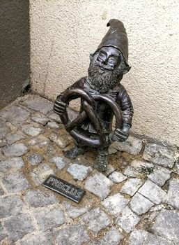 Dwarf gnomes sculpture with magnifying glass in downtown of famous polish city. Wroclaw Houses and streets of the city of Wroclaw. Cityscape. High quality photo