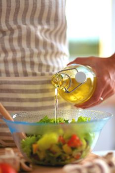 Young woman mixing fresh salad .