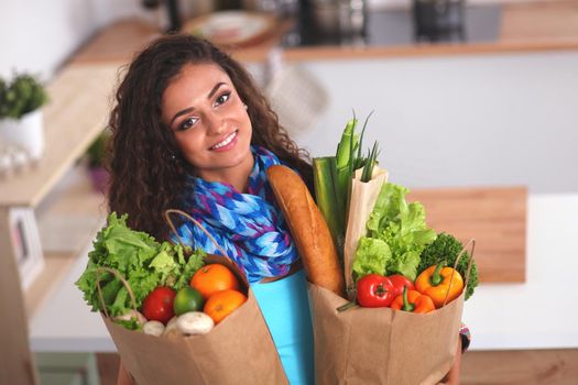 Young woman holding grocery shopping bag with vegetables.