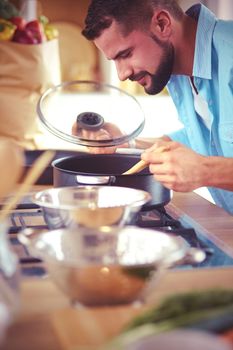 Man following recipe on digital tablet and cooking tasty and healthy food in kitchen at home.
