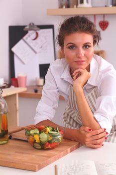 Young woman eating fresh salad in modern kitchen, isolated