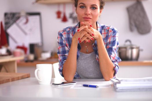 Smiling woman with cup of coffee and newspaper in the kitchen, isolated