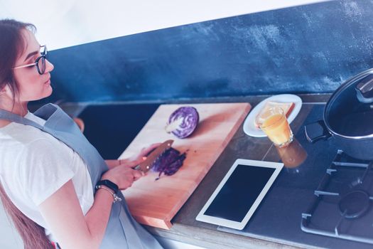 Young woman using a tablet computer to cook in her kitchen.