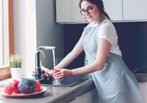 Hands of woman washing vegetables at her kitchen.