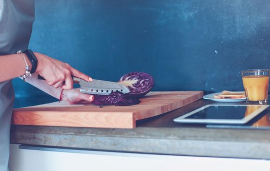 Young woman using a tablet computer to cook in her kitchen.