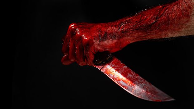 Man holding knife with bloody hand on black background