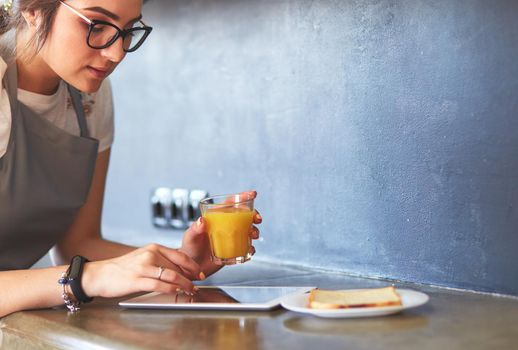 Attractive woman holding a glass of orange juice while standing in the kitchen.