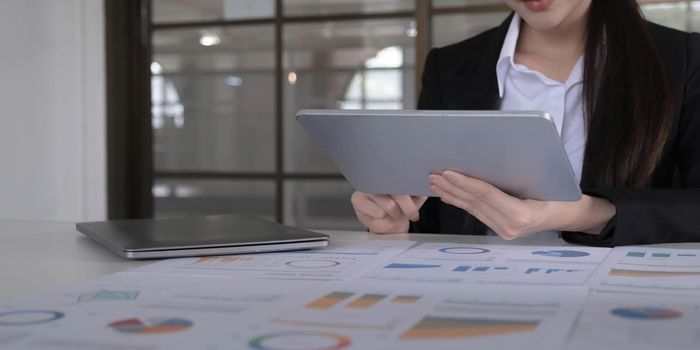 Young asian businesswoman works on tablet with laptop at the office..