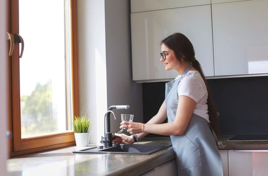 Woman hand's filling the glass of water.