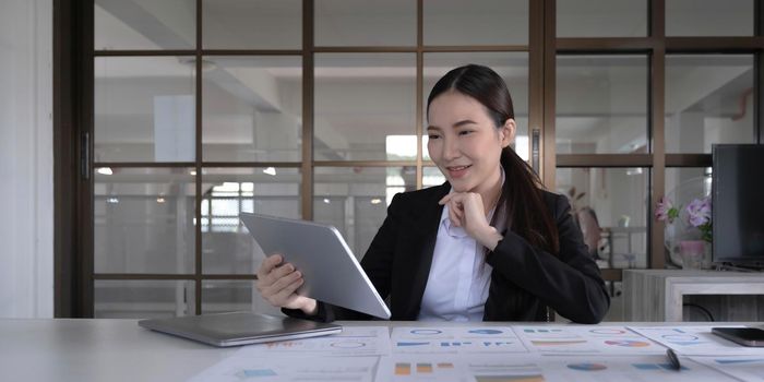 Young asian businesswoman works on tablet with laptop at the office..