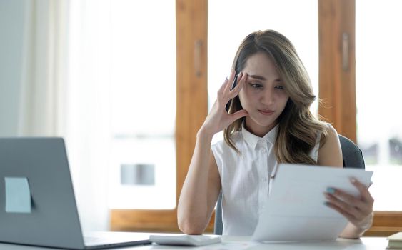 Image of an Asian woman who is tired and overthinking from working with a tablet at the office..