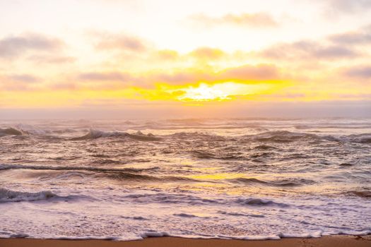 Landscape with sea sunset on beach. Beautiful view on ocean horizon with orange sun and clouds, dramatic mood