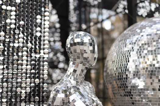 Male mannequin covered with slices of a mirror on a black background mr disco. a super cool disco club character against sparkling background