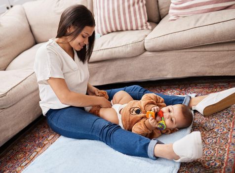 Dressing babies is a contact sport. a young mother dressing her son while he chews a toy