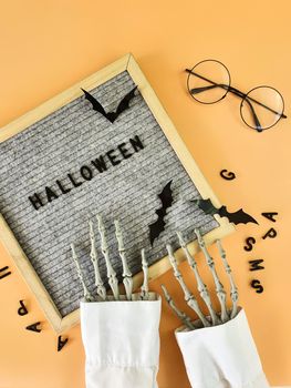 The skeleton's hand collects the word Halloween in a frame . High quality photo