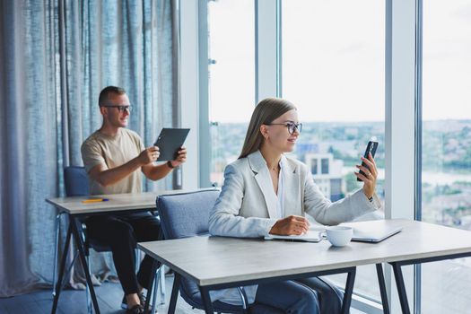 Portrait of a female manager in formal attire doing office work and talking on the phone, a successful european female boss in optical glasses for vision correction, posing at her desk