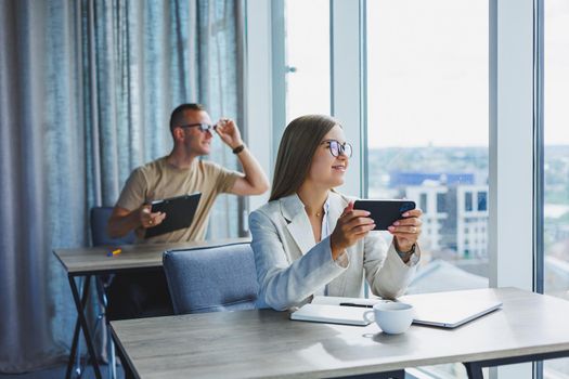 Portrait of a female manager in formal attire doing office work and talking on the phone, a successful european female boss in optical glasses for vision correction, posing at her desk