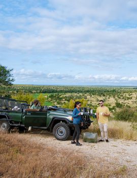 Asian women and European men on safari game drive in South Africa Kruger national park. a couple of men and women on safari. Tourist in a jeep looking sunset on safari