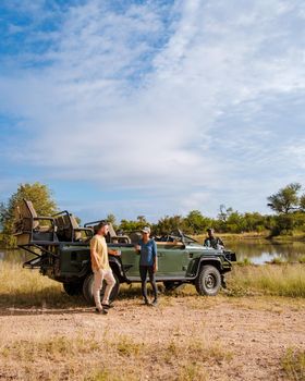 Asian women and European men on safari game drive in South Africa Kruger national park. a couple of men and women on safari. Tourist in a jeep looking sunset on safari