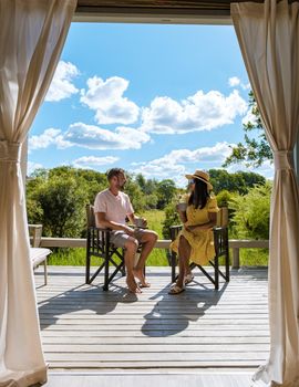 couple on safari in South Africa, Asian women and European men at a tented camp lodge during the safari. Couple of men and a woman are on vacation in South Africa