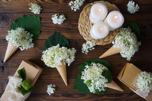 Hydrangea flowers are collected in ice cream cones and lie on the table with gifts. High quality photo