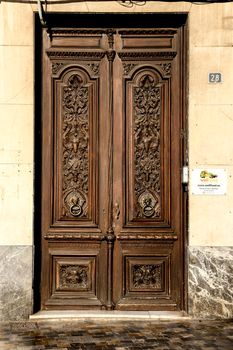 Cartagena, Murcia, Spain- July 18, 2022: Beautiful carved wooden door and vintage lion face shaped knocker in Spain