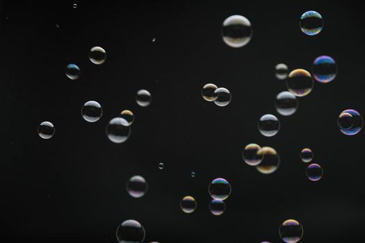 Flying soap bubbles on black background. Abstract soap bubbles with colorful reflections. Soap bubbles in motion background.