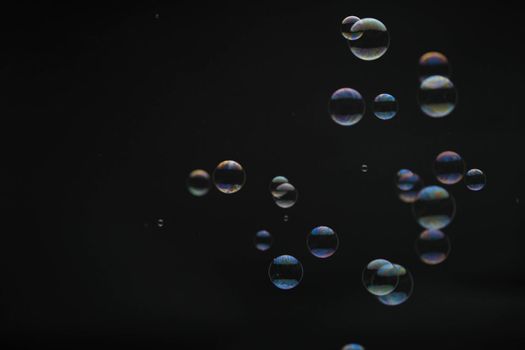 Flying soap bubbles on black background. Abstract soap bubbles with colorful reflections. Soap bubbles in motion background.