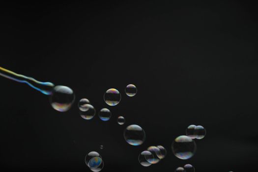 Flying soap bubbles on black background. Abstract soap bubbles with colorful reflections. Soap bubbles in motion background.