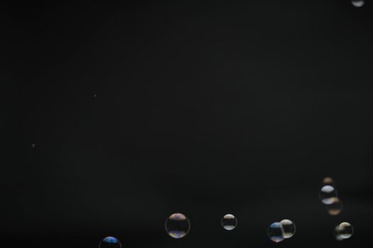 Flying soap bubbles on black background. Abstract soap bubbles with colorful reflections. Soap bubbles in motion background.