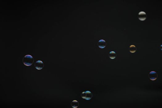 Flying soap bubbles on black background. Abstract soap bubbles with colorful reflections. Soap bubbles in motion background.