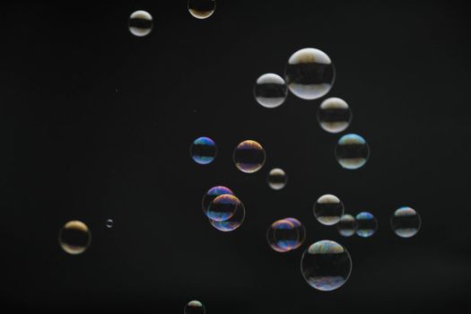 Flying soap bubbles on black background. Abstract soap bubbles with colorful reflections. Soap bubbles in motion background.