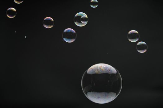 Flying soap bubbles on black background. Abstract soap bubbles with colorful reflections. Soap bubbles in motion background.