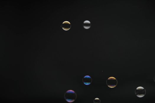 Flying soap bubbles on black background. Abstract soap bubbles with colorful reflections. Soap bubbles in motion background.