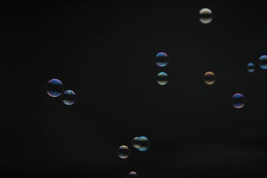 Flying soap bubbles on black background. Abstract soap bubbles with colorful reflections. Soap bubbles in motion background.