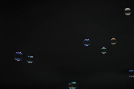 Flying soap bubbles on black background. Abstract soap bubbles with colorful reflections. Soap bubbles in motion background.