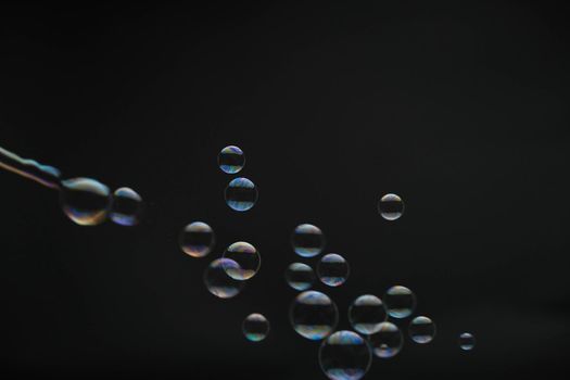 Flying soap bubbles on black background. Abstract soap bubbles with colorful reflections. Soap bubbles in motion background.