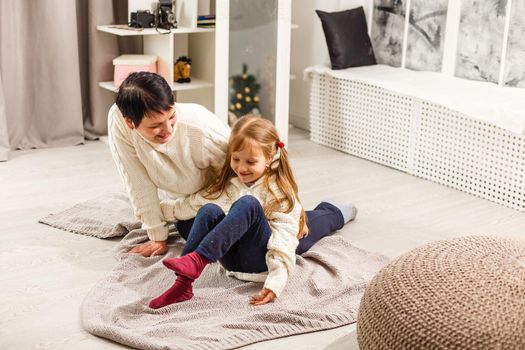 holidays, celebration, family and people concept - happy mother and little girl with gift box over living room and christmas background.