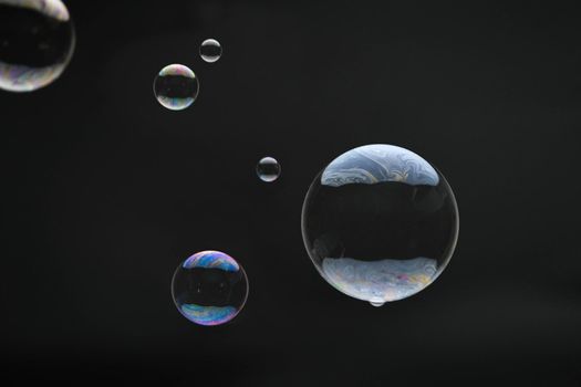 Flying soap bubbles on black background. Abstract soap bubbles with colorful reflections. Soap bubbles in motion background.