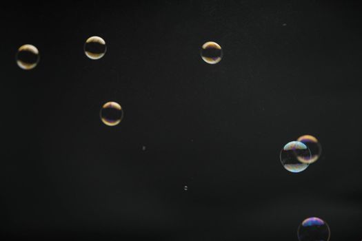 Flying soap bubbles on black background. Abstract soap bubbles with colorful reflections. Soap bubbles in motion background.