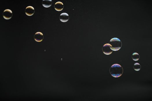 Flying soap bubbles on black background. Abstract soap bubbles with colorful reflections. Soap bubbles in motion background.