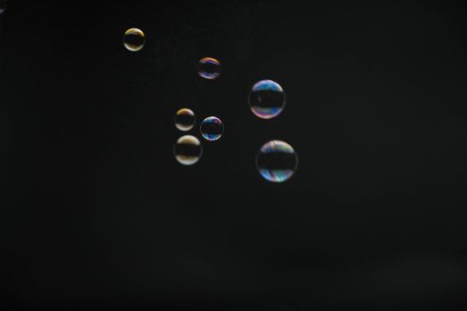 Flying soap bubbles on black background. Abstract soap bubbles with colorful reflections. Soap bubbles in motion background.