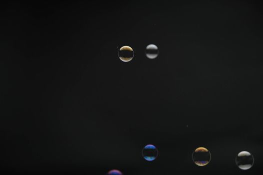 Flying soap bubbles on black background. Abstract soap bubbles with colorful reflections. Soap bubbles in motion background.