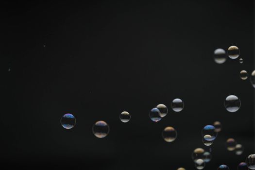 Flying soap bubbles on black background. Abstract soap bubbles with colorful reflections. Soap bubbles in motion background.