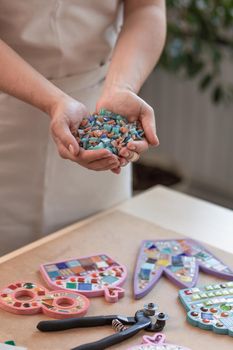 Workplace of the mosaic master: women's hands holding mosaic details in the process of making a mosaic. Close-up