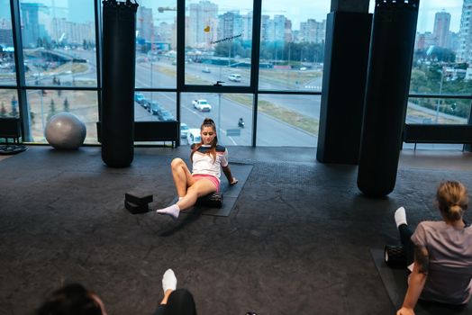 Young woman using a foam roller while doing stretching exercises in the gym.