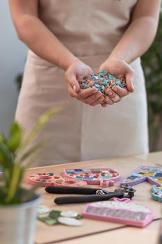 Workplace of the mosaic master: women's hands holding mosaic details in the process of making a mosaic. Close-up